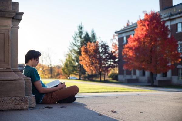 Student sitting on campus of Unversity of Rochester